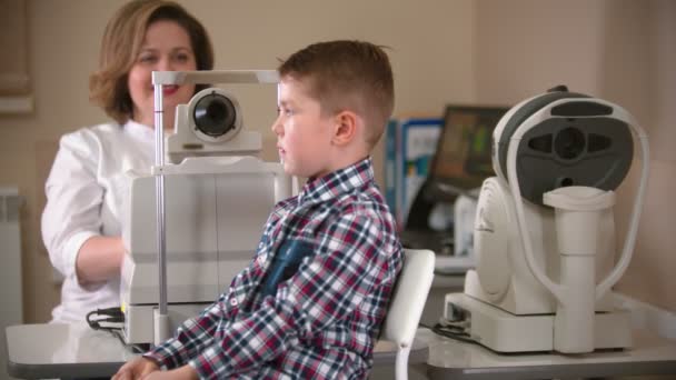 A treatment in eye clinic - checking little boys eye vision indoors — 비디오