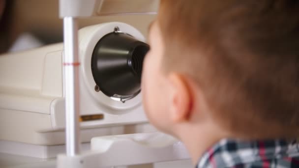 Pojke som behandlas på ögonkliniken - en kvinnlig läkare som kontrollerar små pojkars syn på ögonen — Stockvideo
