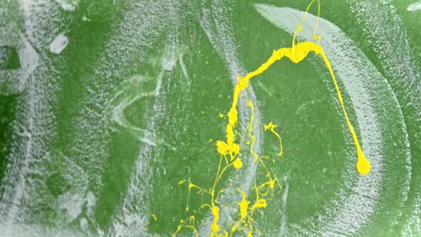 Uma pessoa espirra tinta de cor amarela brilhante na parede usando um pincel — Vídeo de Stock