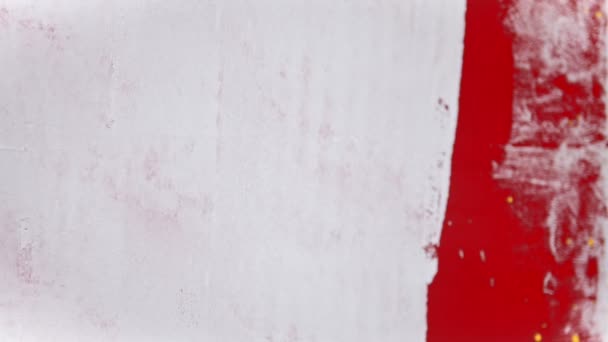 Une personne éclabousse de peinture de couleur jaune vif sur le mur blanc à l'aide d'un pinceau 