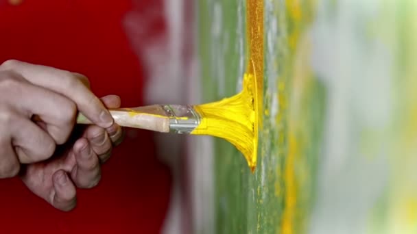 Penseel bedekt met gele verf tegen de muur duwen - de penseel tegen de muur draaien — Stockvideo