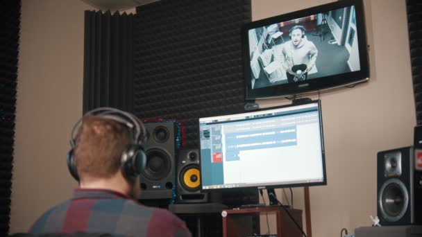 Een man geluidstechnicus kijken naar de rapper tijdens het opnemen van zijn audio tracks — Stockvideo