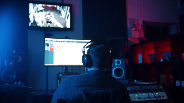 A man sound engineer in headphones working in the neon sound recording studio - recording a rap track — 비디오