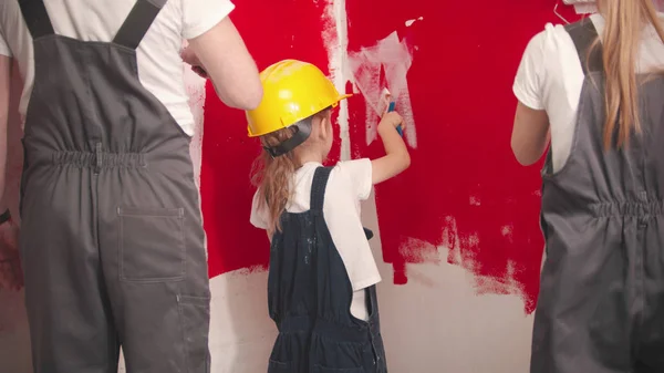 Family are painting a red wall with white paint — 스톡 사진