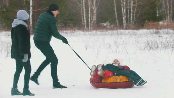 Um homem rola seu filho no trenó inflável — Vídeo de Stock