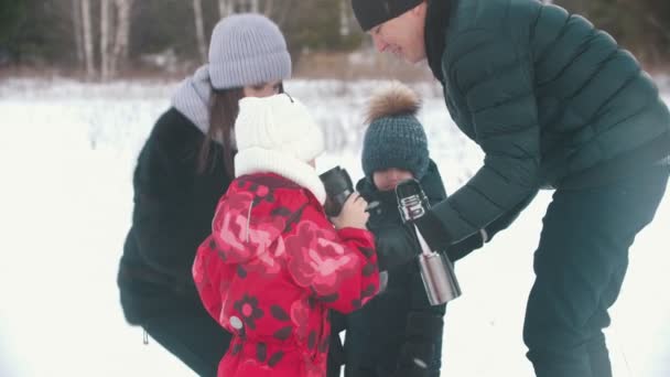 Familia feliz bebiendo té del termo al aire libre cerca del bosque — Vídeo de stock