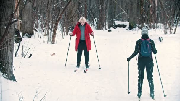 Una mujer rubia caminando sobre el esquí en el bosque — Vídeos de Stock