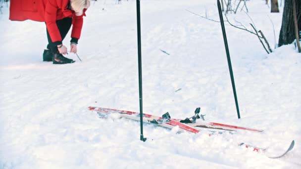 Uma mulher se prepara para ficar no esqui amarre seus sapatos — Vídeo de Stock