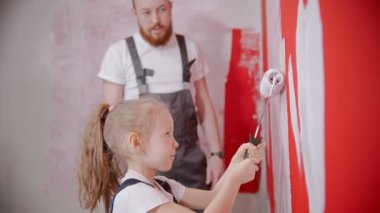 Dad teaching his little daughter how to paint walls correctly