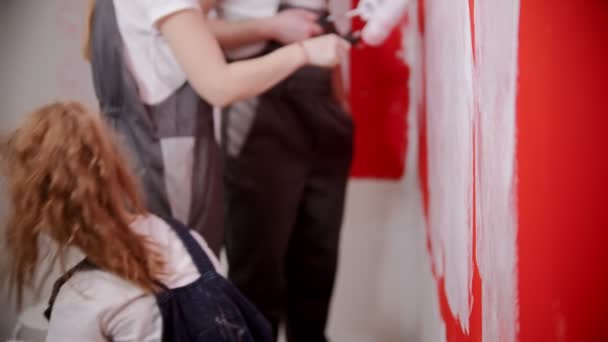 Дівчина занурює пензлик у фарбу і починає фарбувати стіну — стокове відео