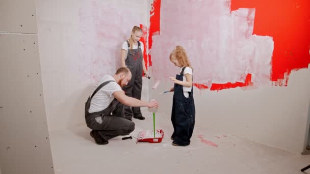 Мама и дочь смотрят, как отец заливает зеленую краску в поднос. — стоковое видео