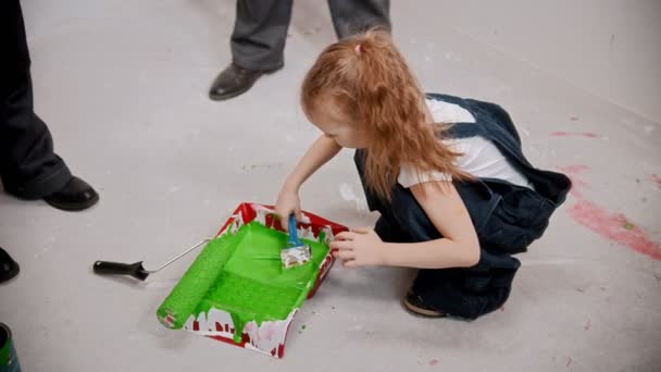 Hija están revolviendo con un pincel de pintura verde en una bandeja — Vídeos de Stock