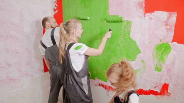 Mam en pap spelen met verf terwijl dochter de muur schildert. — Stockvideo
