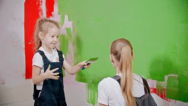 Mom and daughter are playing with a brush and a roller and smearing with paint — 비디오