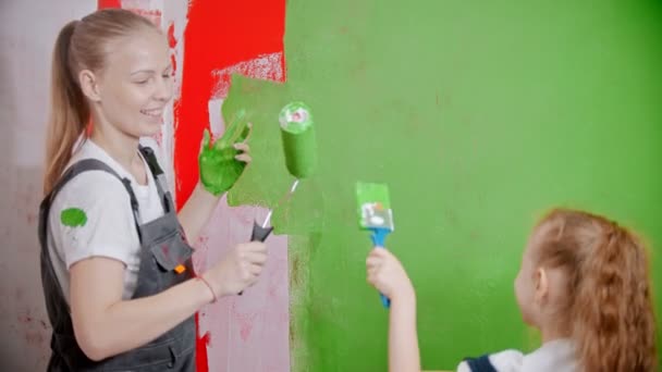Anya és lánya játszik egy ecsettel és görgővel, miközben festik a falakat. — Stock videók