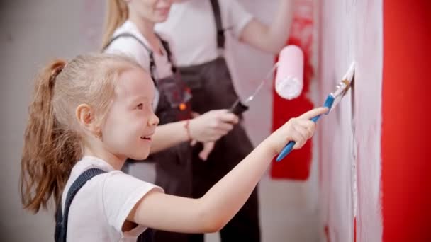 Beautiful little girl is painting the walls with parents — 비디오