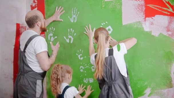 Family are putting their white handprints on a green wall — ストック動画