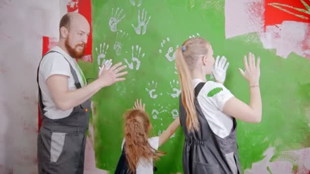 Family are putting their white handprints on a green wall and similng — Stockvideo