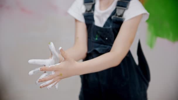 Niña está examinando sus manos en pintura blanca — Vídeos de Stock