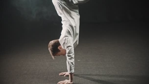 Νεαρός εκπαιδεύει το χορό του στο στούντιο - στέκεται στα χέρια του — Αρχείο Βίντεο