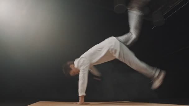 Νεαρός αθλητικός χορευτής περιστρέφεται γύρω από ακουμπώντας τα χέρια του στην ξύλινη σανίδα — Αρχείο Βίντεο