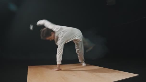 Young athletic man dancer showing a breakdance trick on his hands on the wooden board — 비디오