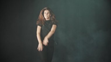 A young attractive woman dancing in dark studio