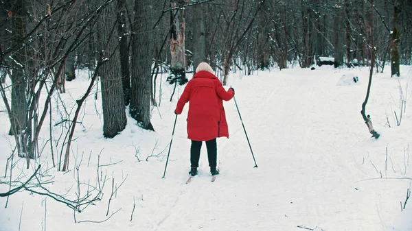 A young blonde woman in red down jacket walking on ski — 스톡 사진