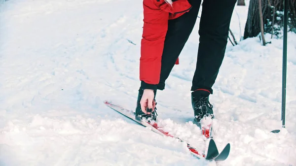 Una mujer con chaqueta roja desmontando sus botas del esquí — Foto de Stock