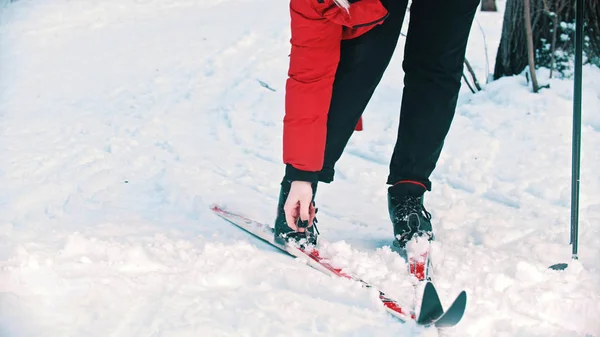 Kırmızı ceketli bir kadın botlarını kayaktan indiriyor. — Stok fotoğraf