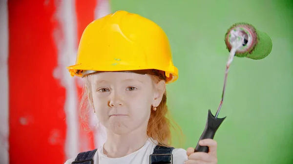 Une petite fille tenant un rouleau de peinture et regardant la caméra — Photo