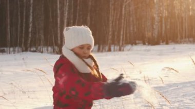 A little girl is spinning throwing snow and laughing