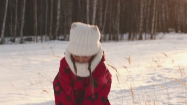 A little girl is throwing snow into the air and laughing