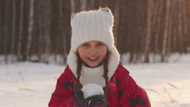Маленька дівчинка дме сніг з долоні і посміхається — стокове відео