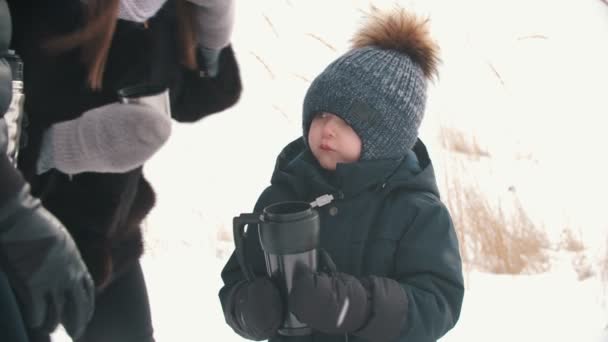 Ein kleiner Junge trinkt Tee aus dem Thermobecher — Stockvideo