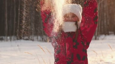 A little girl is throwing snow into the air and smiling