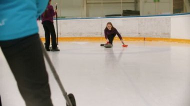 Curling training - a woman skating on the ice field with a granite stone and releasing it