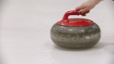 Curling - a granite stone on the ice field with red handle
