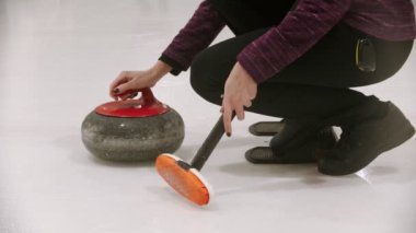 Curling - a young woman pushes off from the stand with granite stone