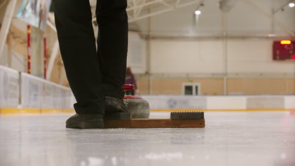 Curling training in sportcomplex - een vrouw duwt de granieten steen naar voren — Stockvideo