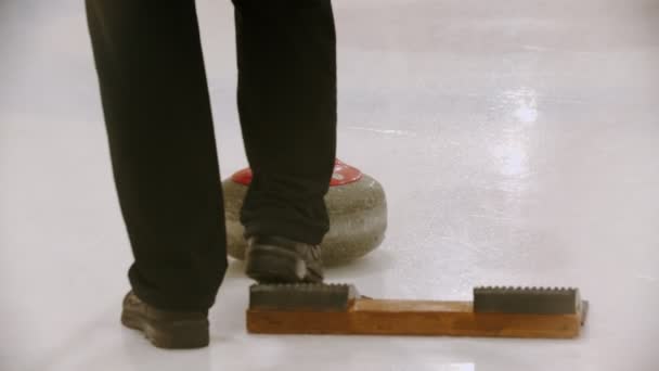 Curling - en ung kvinde skubber væk fra stativet med granitsten på skøjtebanen – Stock-video