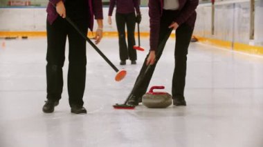 Curling - leading granite stone on the ice - clearing the ice before the stone