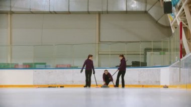 Curling training indoors - team group of three women leading the granite stone
