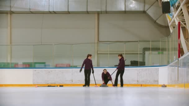 Curling training indoors - team group of three women leading the granite stone — 图库视频影像