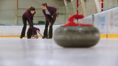 Curling training - leading granite stone on the ice - two women rubbing the ice before the stone - kicking others hostile stone from the point