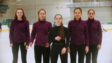 Curling training - the judge standing on the ice rink with her women students - crossing their hands on the chest