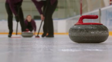 Curling training - a granite stone biter with red handle - playing curling on the background