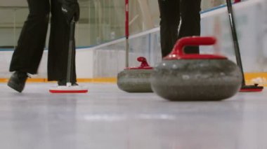 Curling training on the ice rink- a granite stone biter with red handle hitting another biter of opposite team