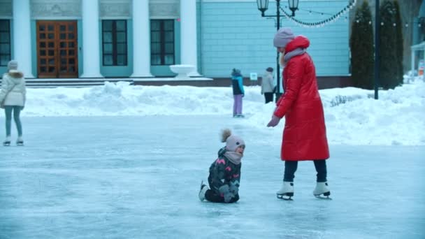 Uma jovem mãe patinando no gelo com seus filhos - levantando seu filho do gelo — Vídeo de Stock