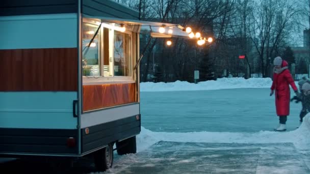 A young woman mother with her children walking out from the ice rink to a little shop — Stock Video